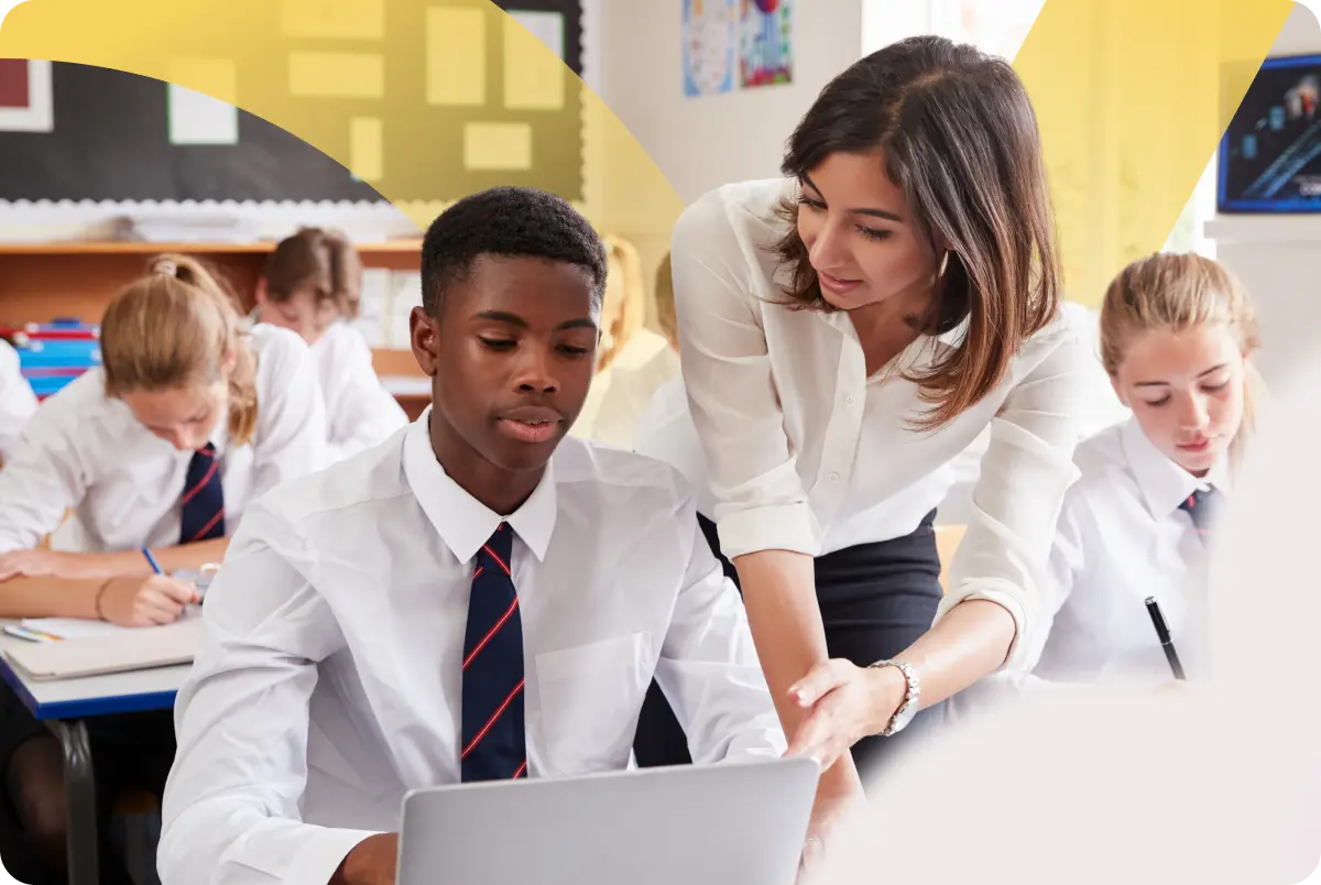 Teacher supporting a student on a laptop in an independent school classroom
